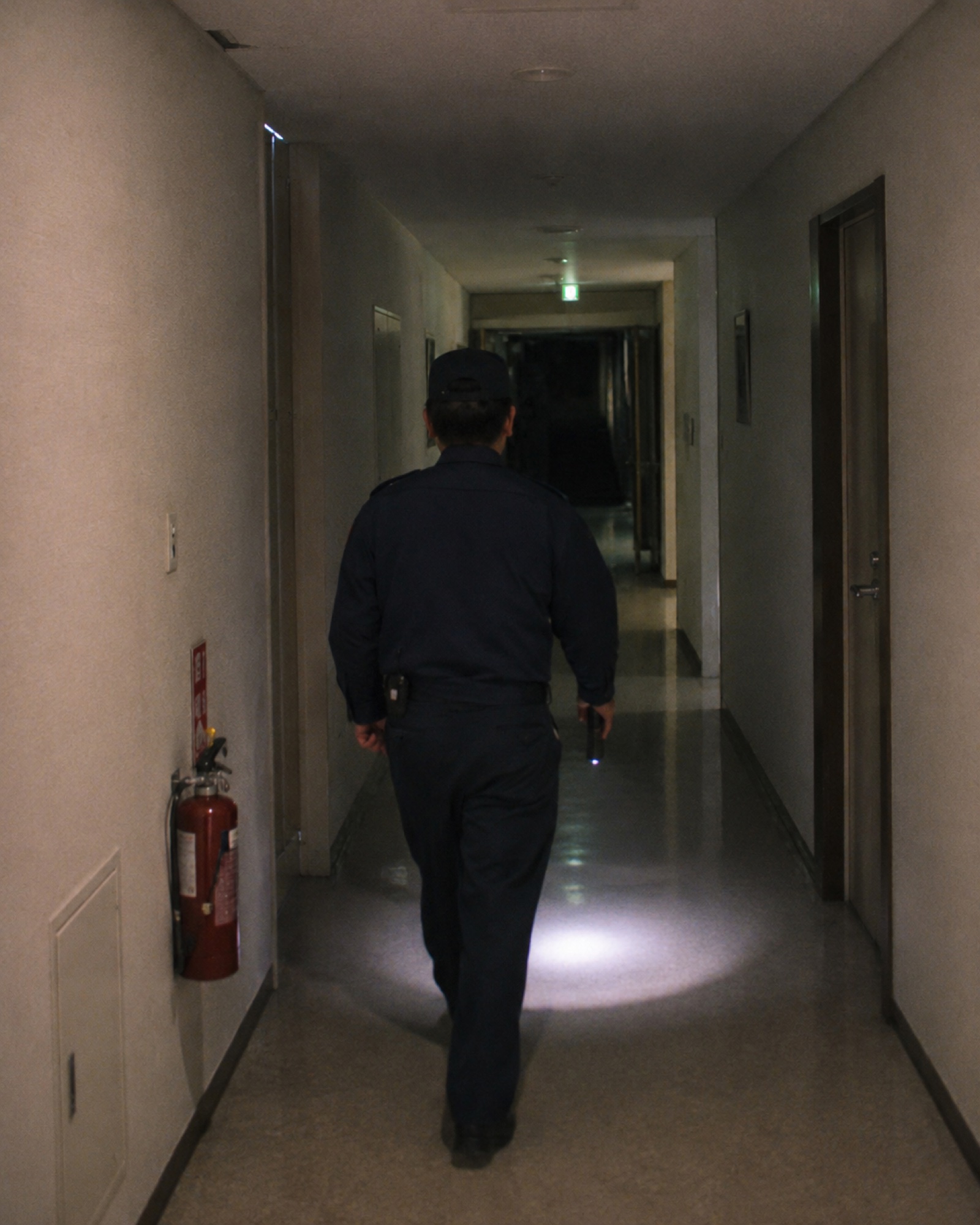 夜間、施設を巡回する警備員の後ろ姿